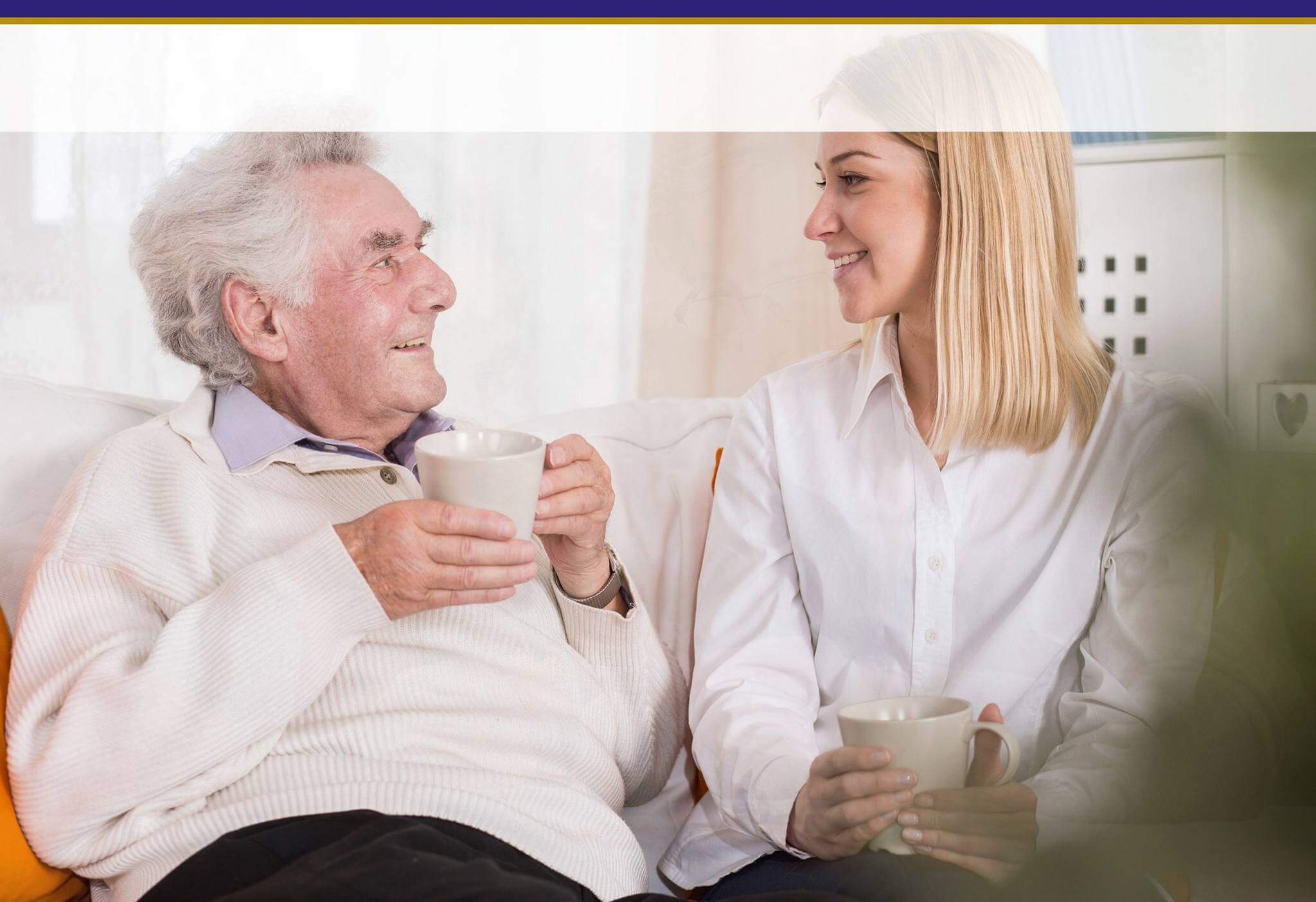 Alter Mann und polnische Pflegekraft sitzen auf einem Sofa